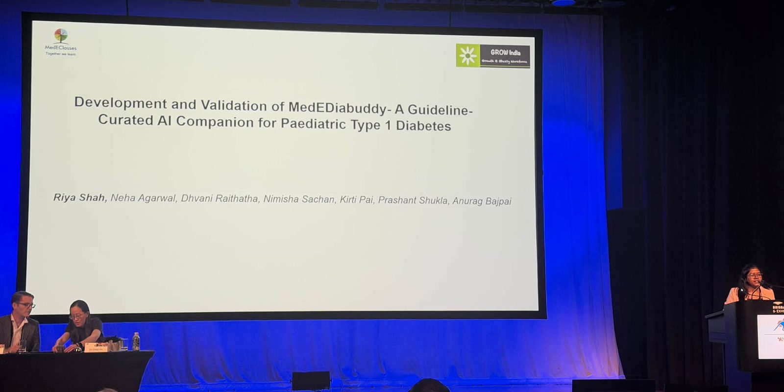 Dr Riya Shah at the podium presenting the MedEDiabuddy development and validation study, with the title slide on screen